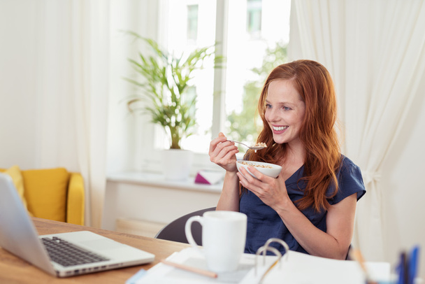 Woman eating breakfast and catching up on news - Foto, Bild