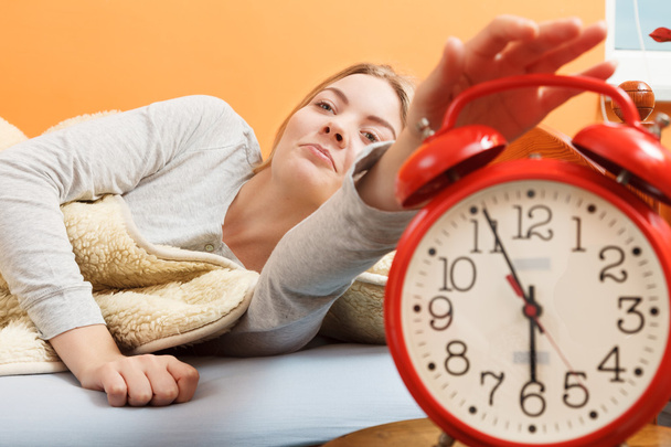 Woman waking up turning off alarm clock in morning - Foto, afbeelding