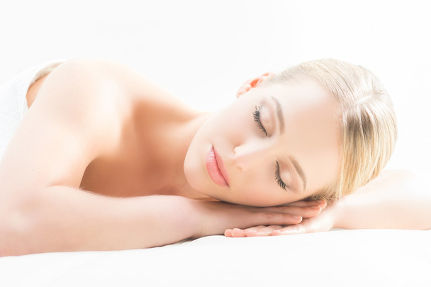 Beautiful young woman having leisure lying in a mat in spa - Photo, image