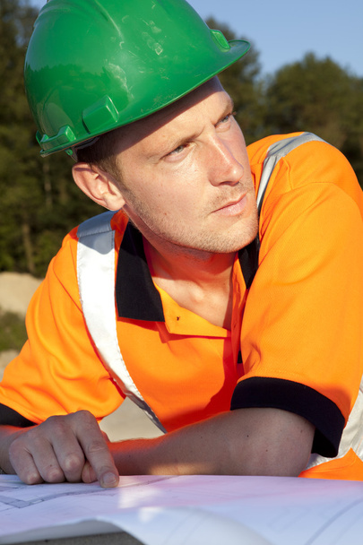 Ручний працівник, який дивиться на креслення, будівництво доріг
 - Фото, зображення