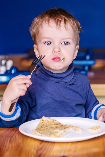 Μικρό παιδί αγόρι σε ένα καφέ που έχει τρώγοντας μια τηγανίτα - Φωτογραφία, εικόνα