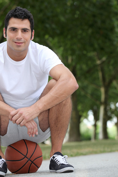 Man crouching on basketball - Фото, зображення