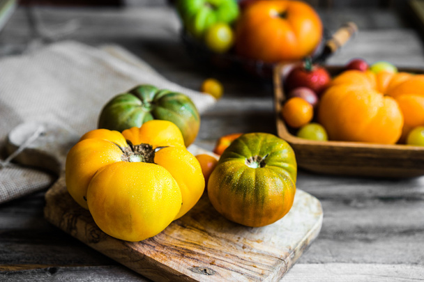 Colorful heirloom tomatoes on rustic wooden background - Photo, image