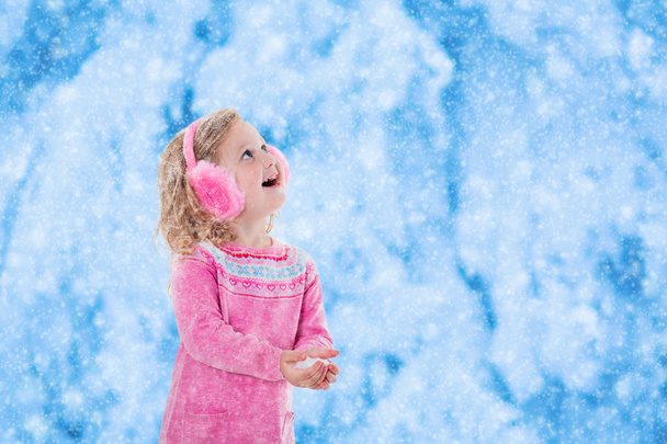 Little girl catching snow flakes - Foto, afbeelding