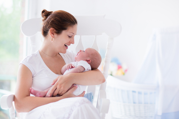 Young mother and newborn baby in white bedroom - 写真・画像