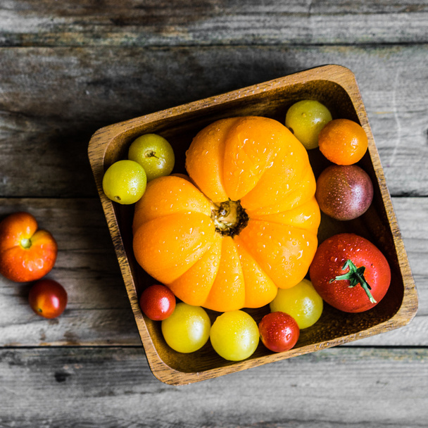 Colorful heirloom tomatoes on rustic wooden background - Foto, afbeelding