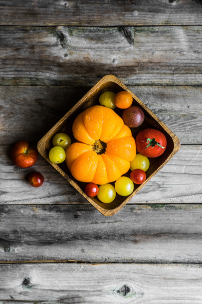 Colorful heirloom tomatoes on rustic wooden background - Foto, imagen