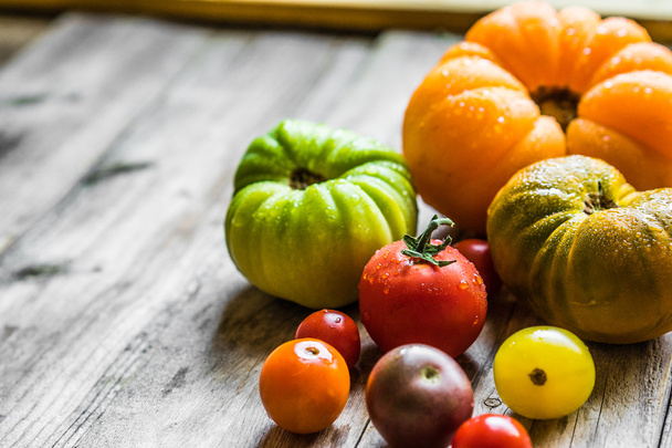 Colorful heirloom tomatoes on rustic wooden background - Photo, image