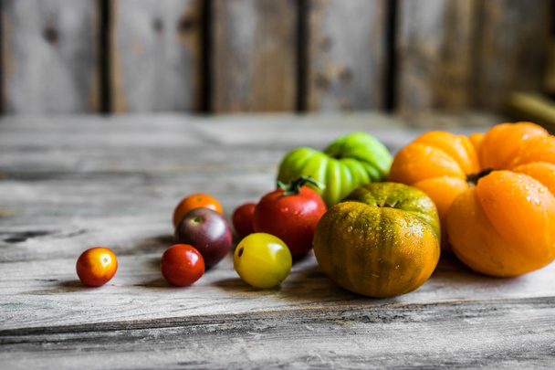 Colorful heirloom tomatoes on rustic wooden background - Fotoğraf, Görsel