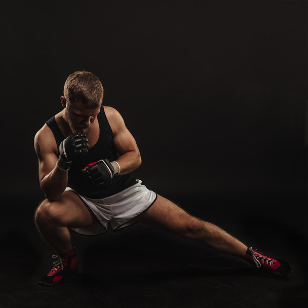 Urheilullinen parrakas nyrkkeilijä käsineillä tummalla taustalla
 - Valokuva, kuva