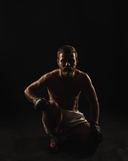Athletic bearded boxer with gloves on a dark background - Fotoğraf, Görsel
