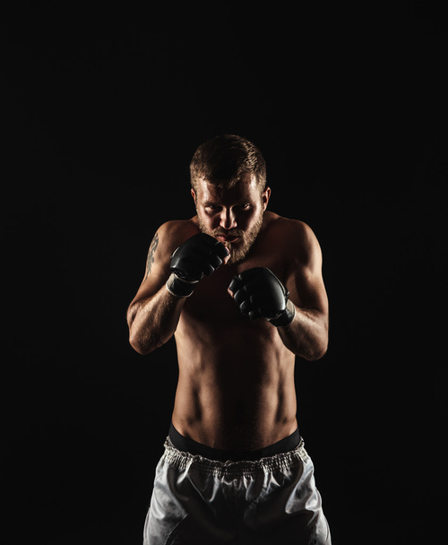 Athletic bearded boxer with gloves on a dark background - Φωτογραφία, εικόνα