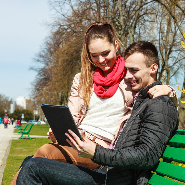 Paar mit Tablet sitzt auf Bank im Freien - Foto, Bild