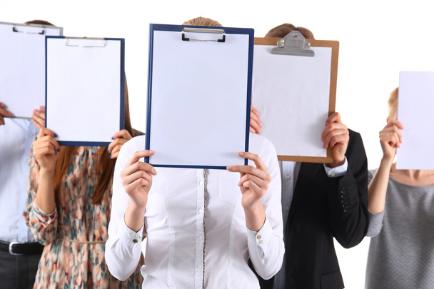 A group of office workers holding clipboards in front of their faces - Zdjęcie, obraz