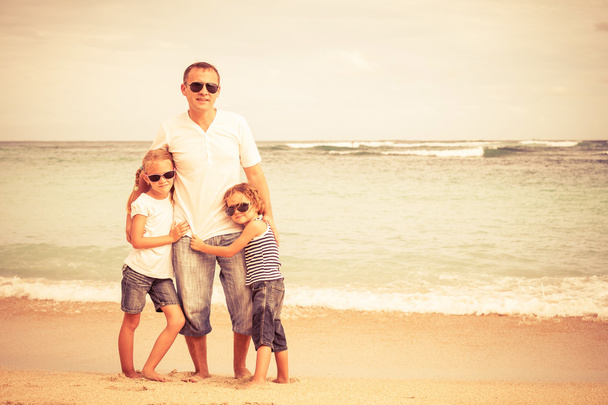 Vader en kinderen spelen op het strand op het moment van de dag. - Foto, afbeelding