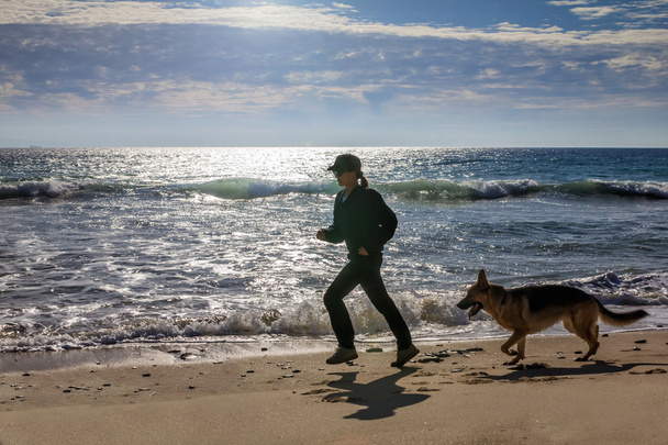 Mulher Jogging no litoral com seu cão
 - Foto, Imagem