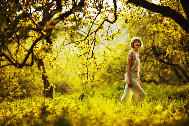 Woman walking in summer apple orchard - Foto, imagen