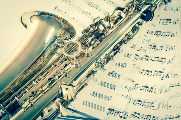 Parte do saxofone deitado nas notas. estilo vintage
 - Foto, Imagem
