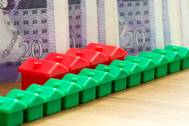 Modèles de maison en plastique rouge vert dans une rangée diagonale avec billets de banque
 - Photo, image