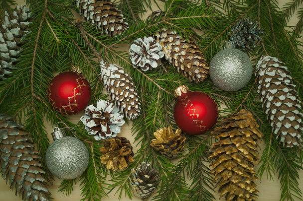 New Year festive decorative background. Christmas tree branch with Christmas toy balls, Christmas tree cones - Photo, Image