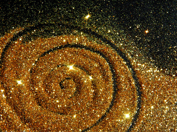 Blurry golden spiral of glitter sparkle on black background like a star galaxy - Photo, Image