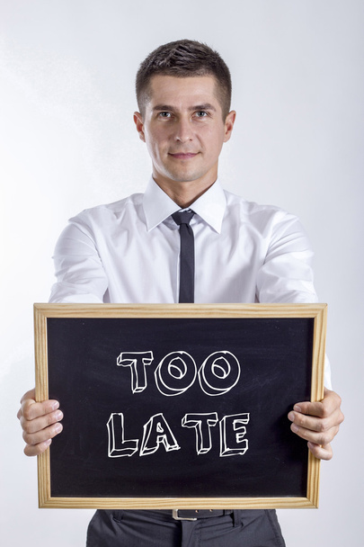 TOO LATE - молодий бізнесмен тримає крейдяну дошку
 - Фото, зображення