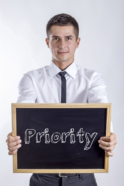 Priorytet - młody biznesmen posiadania tablicy - Zdjęcie, obraz