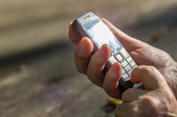 vinger van leeftijd hand aanraken van een mobiele telefoon - Foto, afbeelding