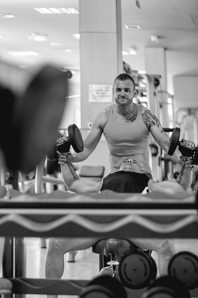 személyi edző segít egy férfi súlyzó - Fotó, kép