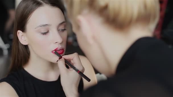 Professzionális make-up: piros kontúr alkalmazása az ajkakon. Közeli. Oldalnézet - Felvétel, videó