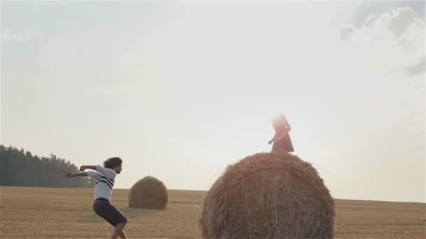 Романтична пара насолоджується заходом сонця в полі. Хлопець стрибає через сірник, щоб дістатися до своєї дівчини. Весела грайлива молода пара піднімається над стосом сіна
 - Кадри, відео