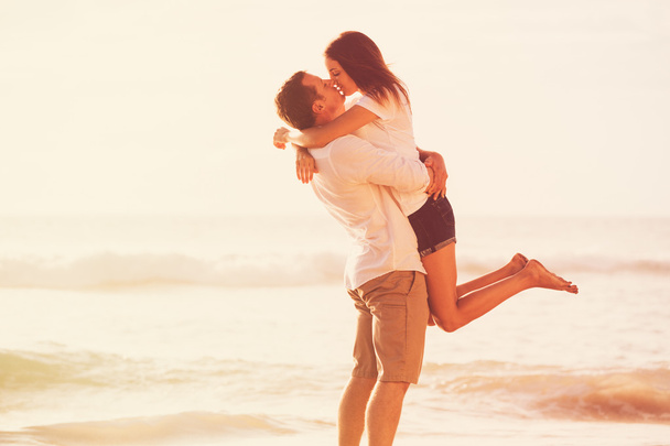 Romantyczna para całuje na plaży o zachodzie słońca - Zdjęcie, obraz