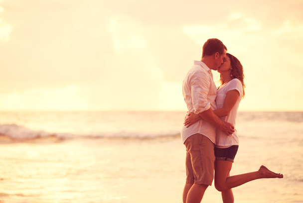 Romantic Couple Kissing on the Beach at Sunset - Фото, изображение