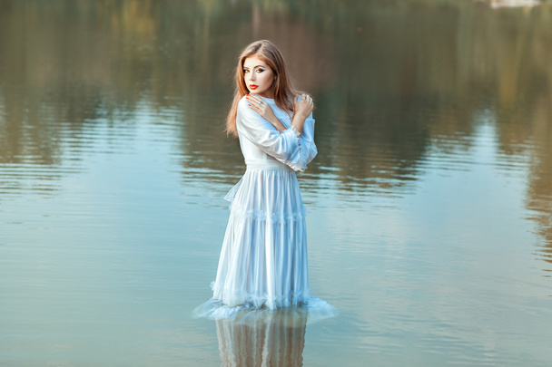 少女は、湖の水で服を浸漬. - 写真・画像