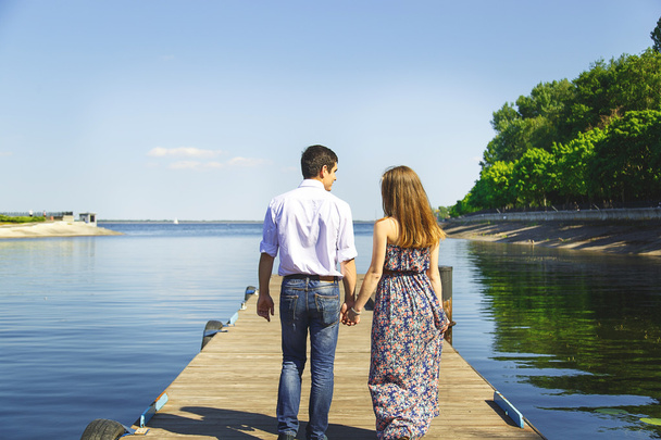 Jonge man en vrouw gaat hand in hand op pier - Foto, afbeelding