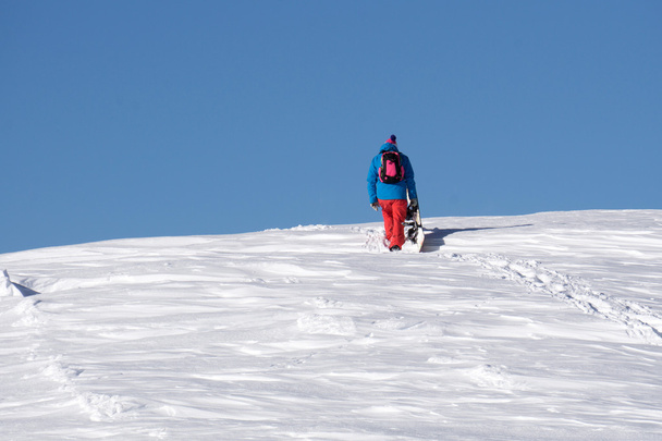 Snowboarder climbing a snowy mountain - Zdjęcie, obraz