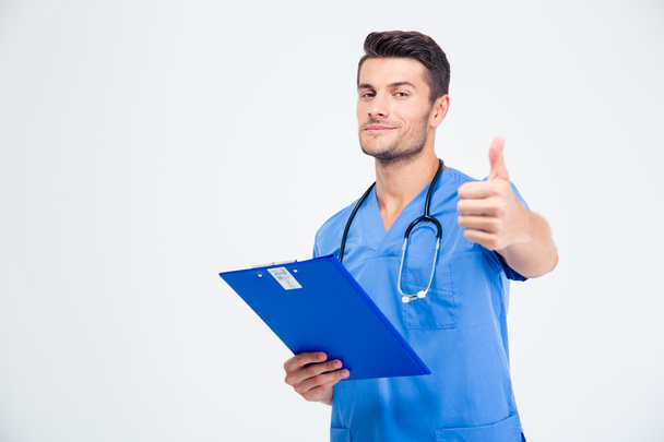 Male doctor holding clipboard and showing thumb up - Foto, Bild