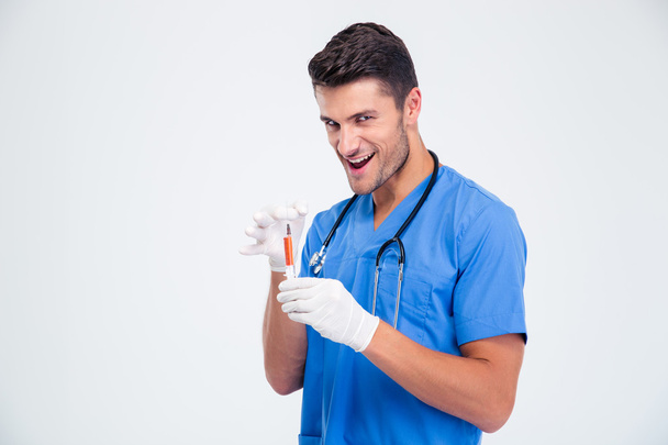 Portrait of a funny male doctor holding syringe - 写真・画像
