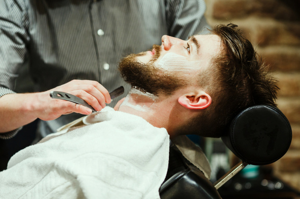 Barbiere rasatura un uomo barbuto
 - Foto, immagini