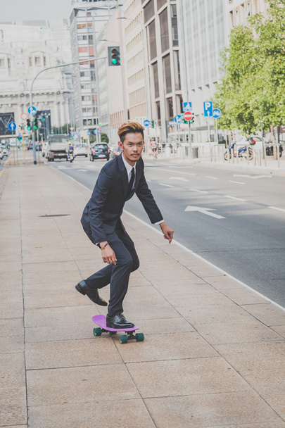 Young handsome Asian model riding his skateboard - Zdjęcie, obraz