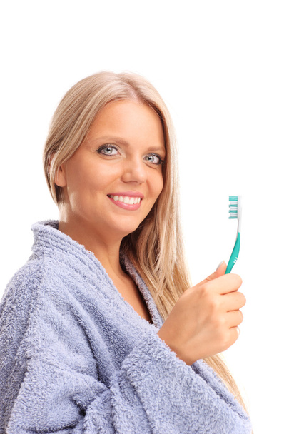 Beautiful blond woman holding a toothbrush - 写真・画像