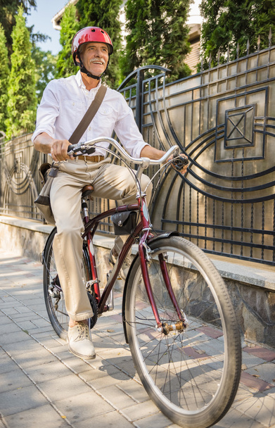 Homme âgé dans le casque est à vélo dans la rue en ville. Concept de vie active personnes âgées
. - Photo, image