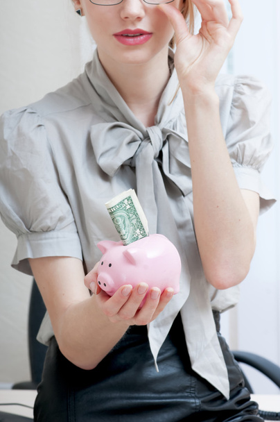 Vrouwelijke hand met piggy bank met een dollar. - Foto, afbeelding