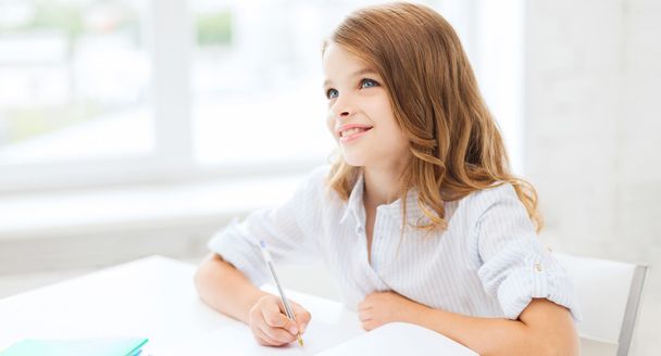 student girl writing in notebook at school - Foto, Bild