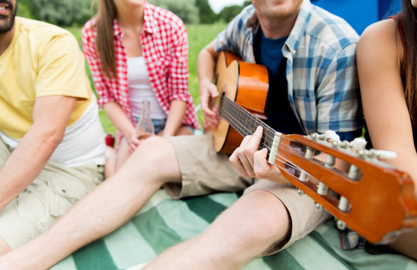 happy friends with drinks and guitar at camping - Foto, Bild