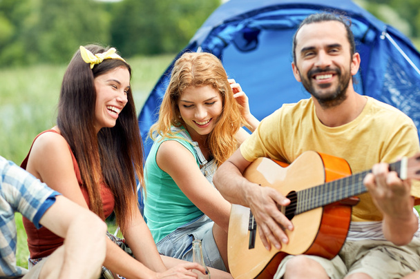 happy friends with drinks and guitar at camping - Photo, image