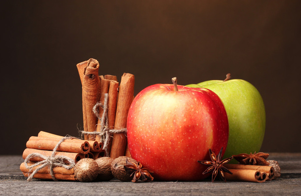 Cinnamon sticks,apples nutmeg and anise on wooden table on brown background - 写真・画像