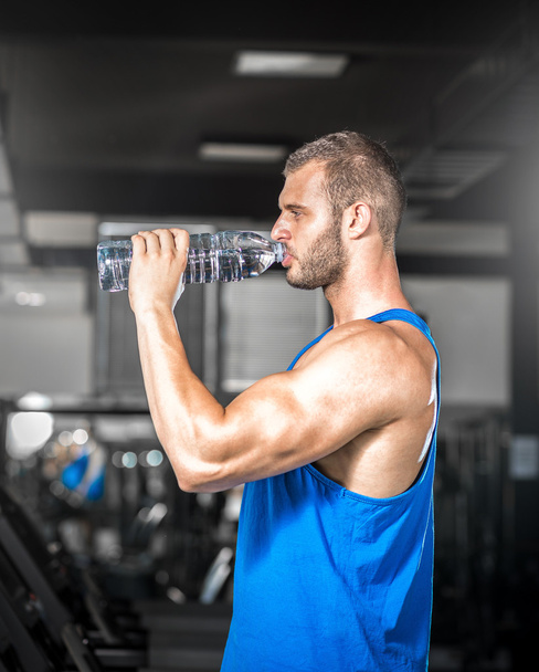 Young man drinking water in gym - Foto, imagen