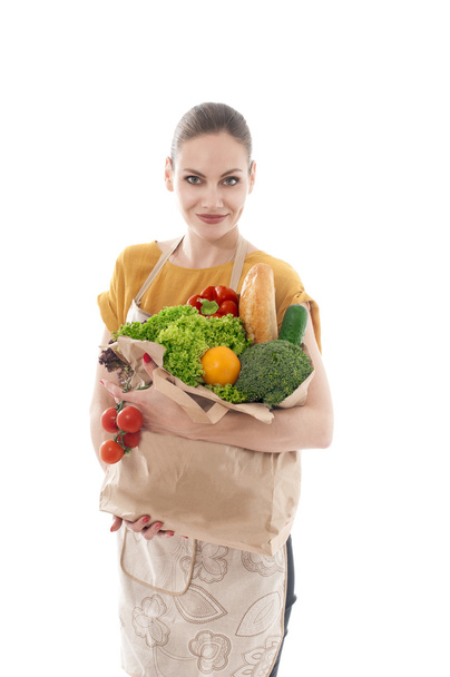 Jonge huisvrouw die een kruidenier zak vol met groenten - Foto, afbeelding