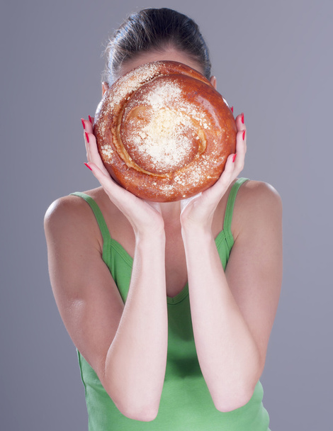 Young woman hiding her face behind a round bun - Photo, Image